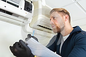 male technician checking air conditioner indoors