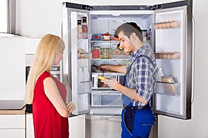 Male Technician Checking Fridge With Digital Multimeter