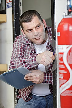 male technician checking red fire extinguisher