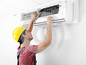 Male technician checking and repairing air conditioner