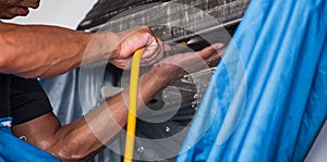 Male technician cleaning air conditioner