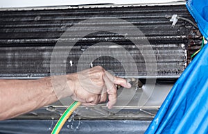 Male technician cleaning air conditioner