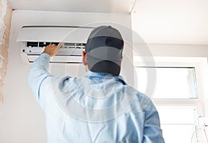 Male technician cleaning air conditioner indoors.