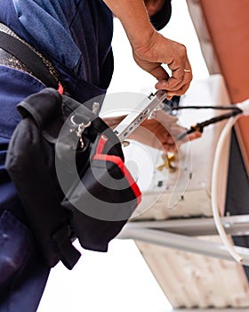 Male technician connects outdoor air conditioning unit to wall of old apartment building.