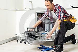 Male Technician Examining Dishwasher With Digital Multimeter