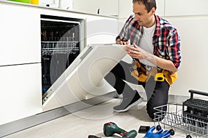 Male Technician Examining Dishwasher With Digital Multimeter