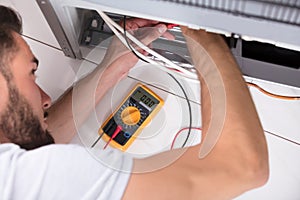 Male Technician Examining Refrigerator photo