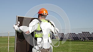 Male technician in exoskeleton carrying photovoltaic panel