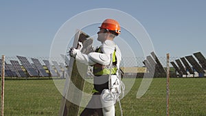 Male technician in exoskeleton carrying photovoltaic panel