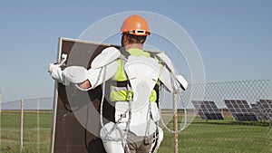 Male technician in exoskeleton carrying photovoltaic panel