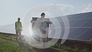 Male technician in exoskeleton carrying solar panel to coworker