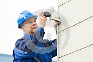 Male Technician Fixing CCTV Camera On Wall