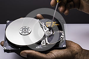 Male technician hand holding and working on  computer hard drive with scewdriver