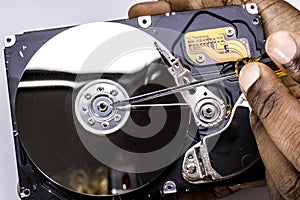 Male technician hand holding and working on dusty computer hard drive with scewdriver