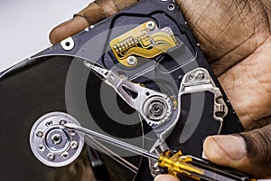 Male technician hand holding and working on dusty computer hard drive with scewdriver