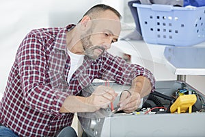 Male technician inspecting and fixing washer and dryer