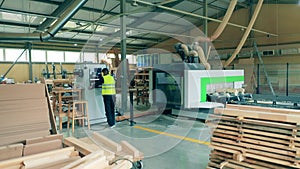 Male technician is managing a massive woodworking machine