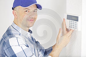 male technician near installed alarm system indoors