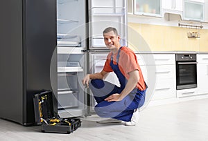 Male technician with pliers repairing refrigerator