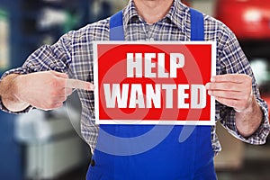 Male Technician Pointing At Help Wanted Sign