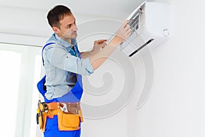 Male technician repairing air conditioner indoors