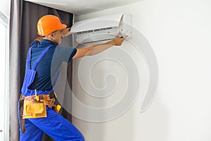 Male technician repairing air conditioner indoors