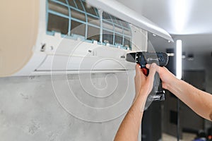 Male technician repairing air conditioner indoors