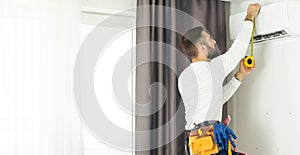 Male technician repairing air conditioner indoors