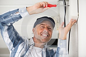 male technician repairing air conditioner with screwdriver