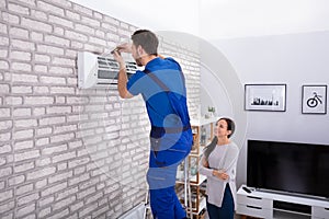 Male Technician Repairing Air Conditioner With Screwdriver photo