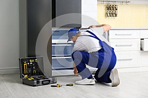 Male technician repairing broken refrigerator