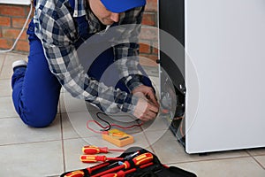 Male technician repairing broken refrigerator, closeup