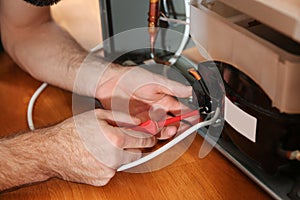 Male technician repairing broken refrigerator, closeup