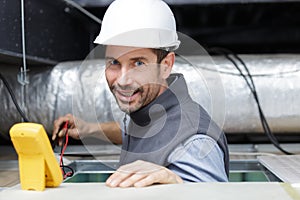 Male technician repairing industrial air conditioner indoors