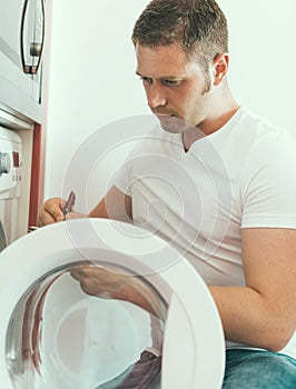 Male technician repairing washing machine.
