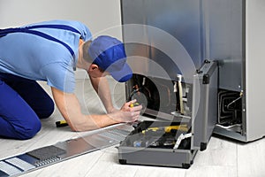 Male technician with screwdriver repairing refrigerator