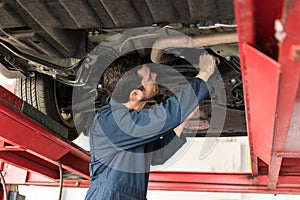 Male Technician Servicing Car In Repair Shop