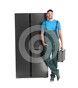 Male technician with tool box near refrigerator on white