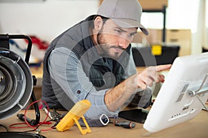 male technician using voltage meter and pc