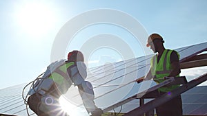 Male technicians assembling solar panel against blue sky