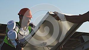 Male technicians assembling solar panel against blue sky