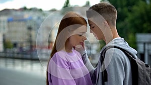 Male teen touching face of beautiful girlfriend at outdoor date, tenderness