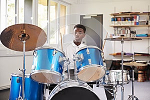 Male Teenage Pupil Playing Drums In Music Lesson