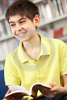 Male Teenage Student In Library Reading Book