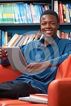 Male Teenage Student Using Digital Tablet In Library