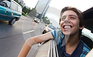 Male teenager in car enjoying city view