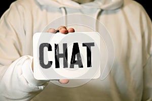 Male teenager holds a blue banner with the word chat against nature background. Social media communication concept