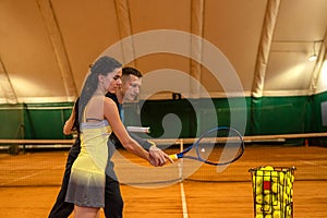 male tennis coach shows a female client how to serve on the court.