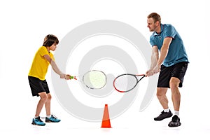 Male tennis player, coach training with teen to play tennis isolated over white studio background. Concept of sport