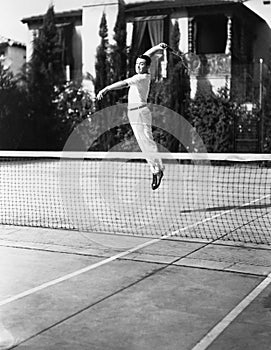 Male tennis player jumping for shot